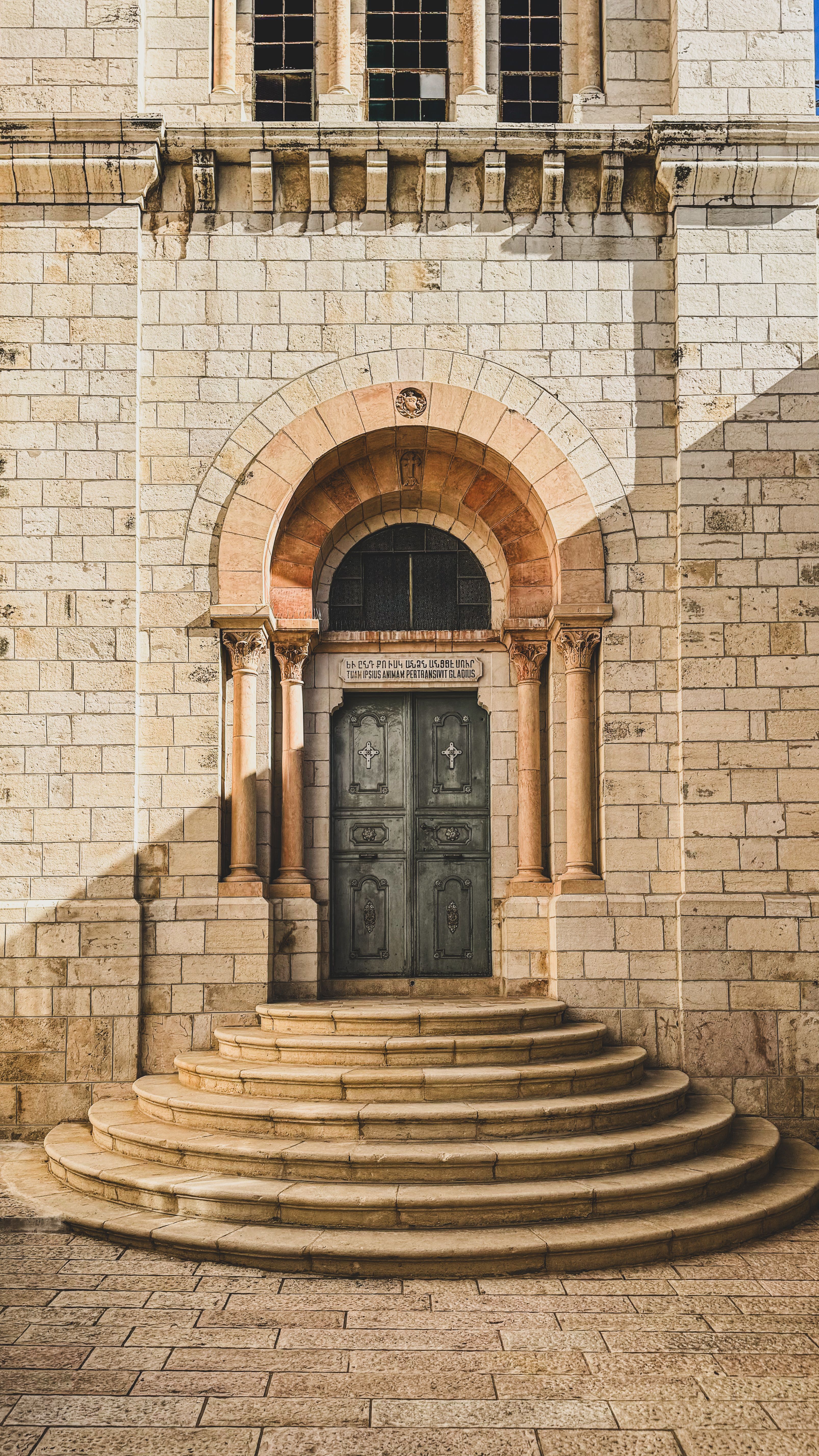 Stone church entrance with arched doorway and steps in Jerusalem's historic district.