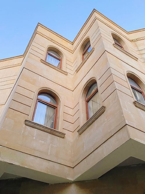Free An upward view of a classic architectural building corner with arched windows. Stock Photo