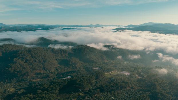 Stunning aerial view of mist-covered mountains and lush forests stretching to the horizon.