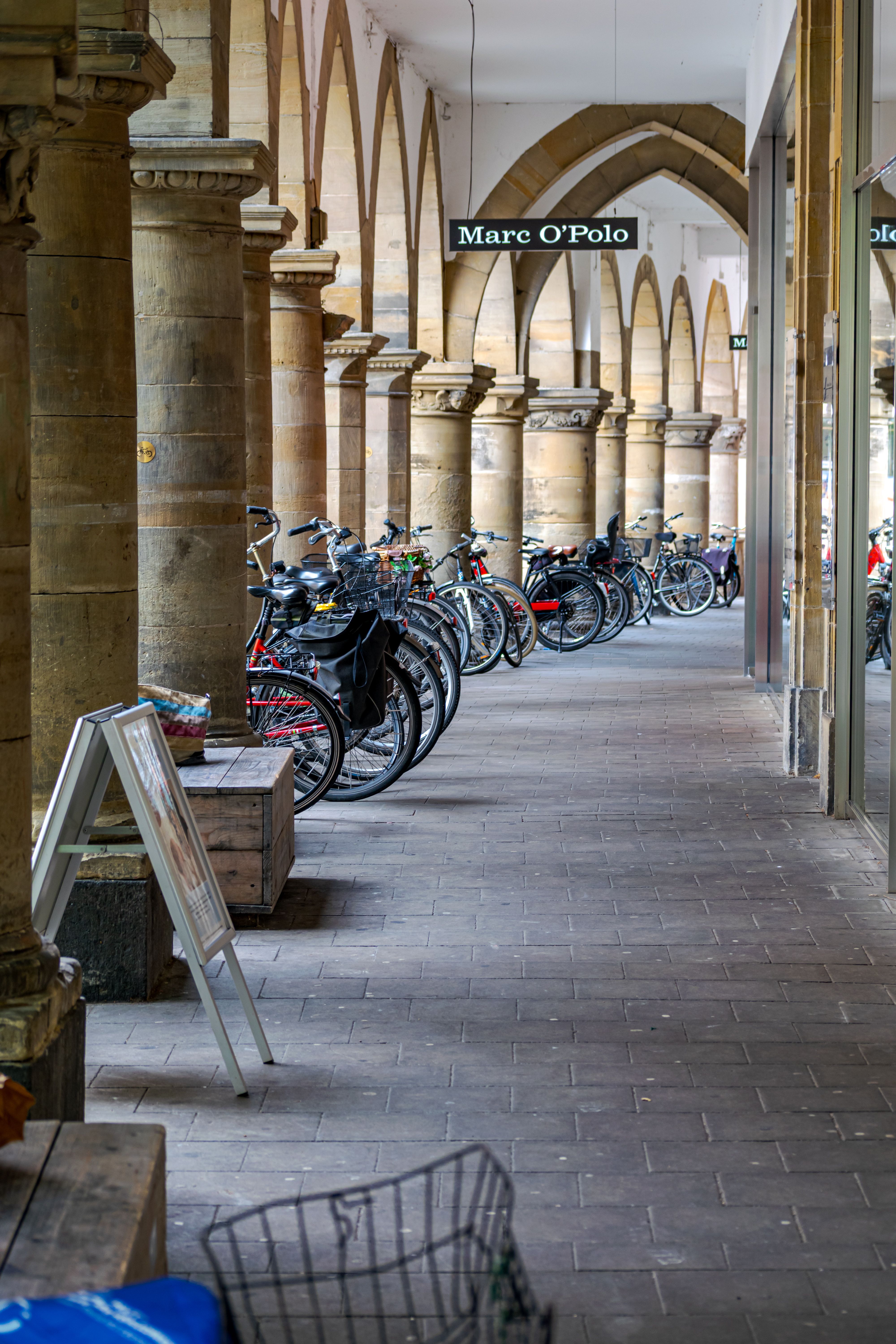 A row of bicycles parked beneath an arched walkway in Münster, Germany.