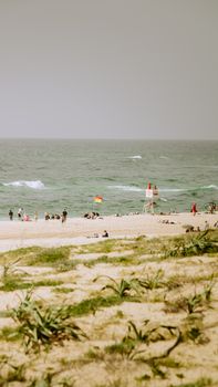 People enjoying a sunny day at a beach in Nouvelle-Aquitaine, France with lifeguards on duty.