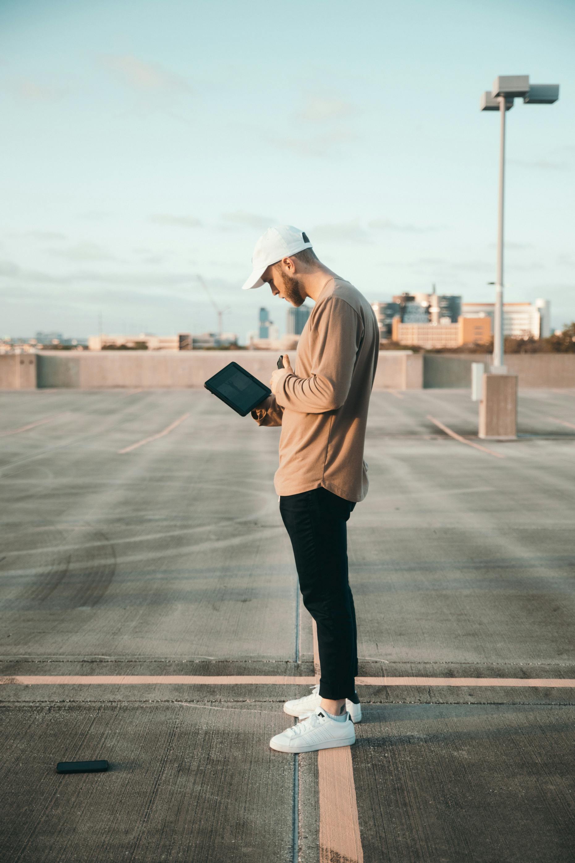 man in brown jacket and black pants holding black tablet computer