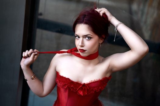 Striking portrait of a woman in a red corset showcasing bold fashion and style.