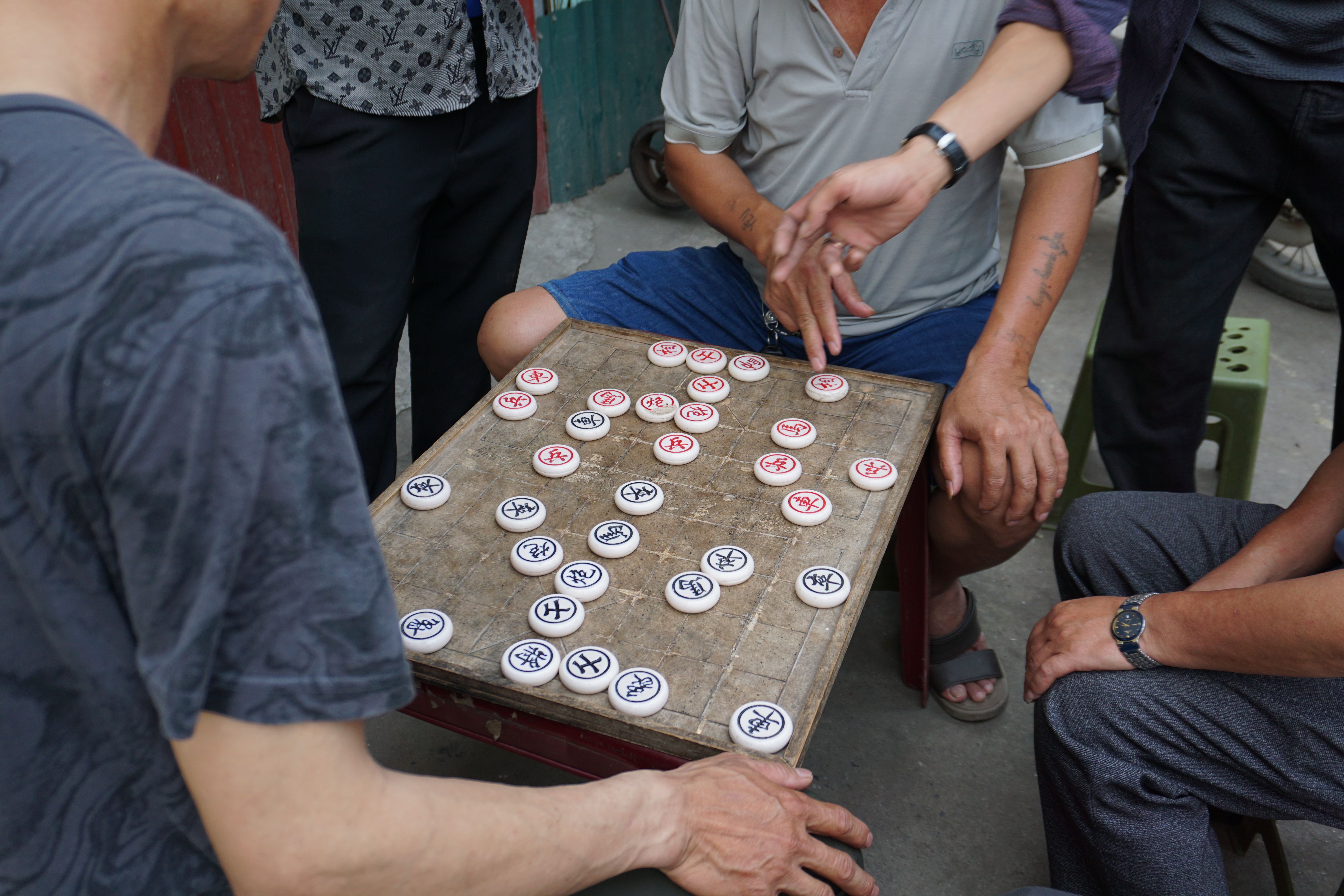 Men play Chinese chess in an outdoor market scene in Ha Giang, Vietnam.