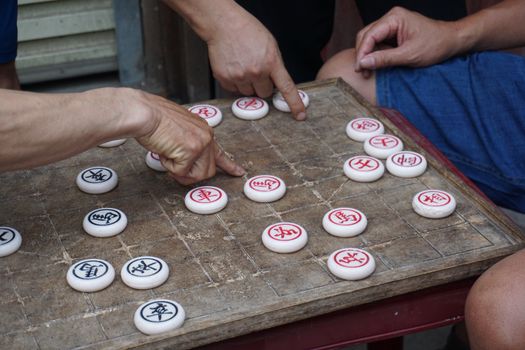 Locals engaged in a game of Chinese chess in a Vietnamese street market, showcasing cultural heritage.