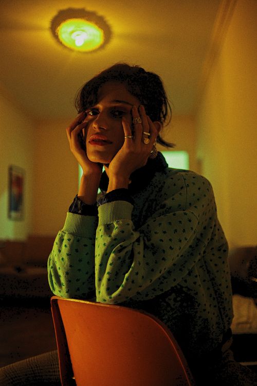 Free A woman in a cozy dimly lit room sits pensively, surrounded by warm ambiance. Stock Photo