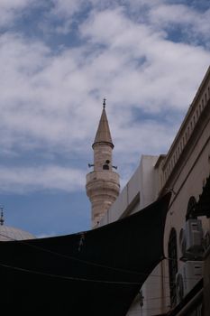 A striking minaret stands against a blue sky in İzmir, Türkiye, showcasing elegant architecture.