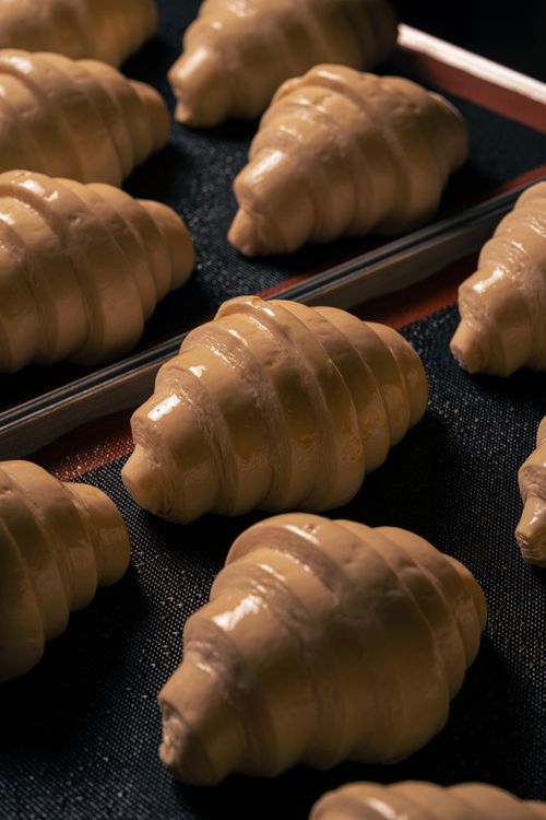 Free Close-up of unbaked croissant dough on a baking tray, highlighting texture and form. Stock Photo