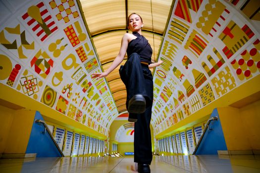 Dynamic fashion portrait in a colorful symmetrical pedestrian tunnel in Jakarta, Indonesia.