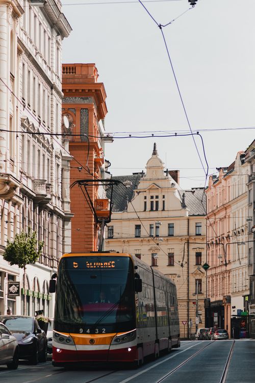 Free A red tram travels through a historic street in Prague, showcasing European architecture. Stock Photo