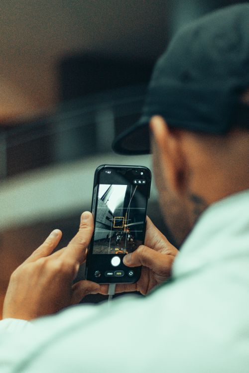 Free Man photographing architectural detail using a smartphone indoors. Stock Photo