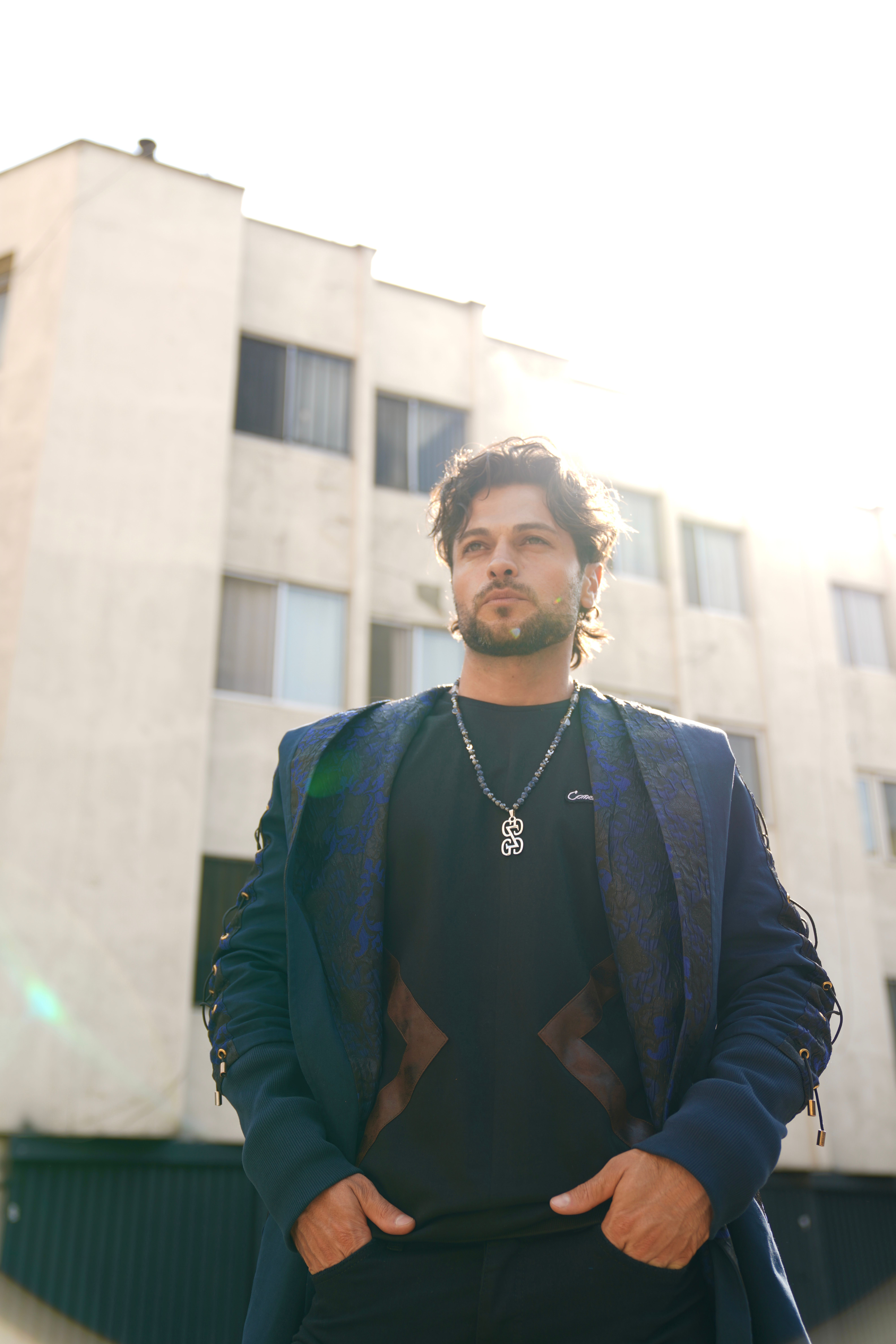 Stylish man in Tehran with backlight by a building.