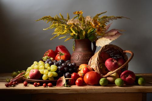 Free A rich still life arrangement featuring a variety of autumn fruits and flowers on a wooden table. Stock Photo