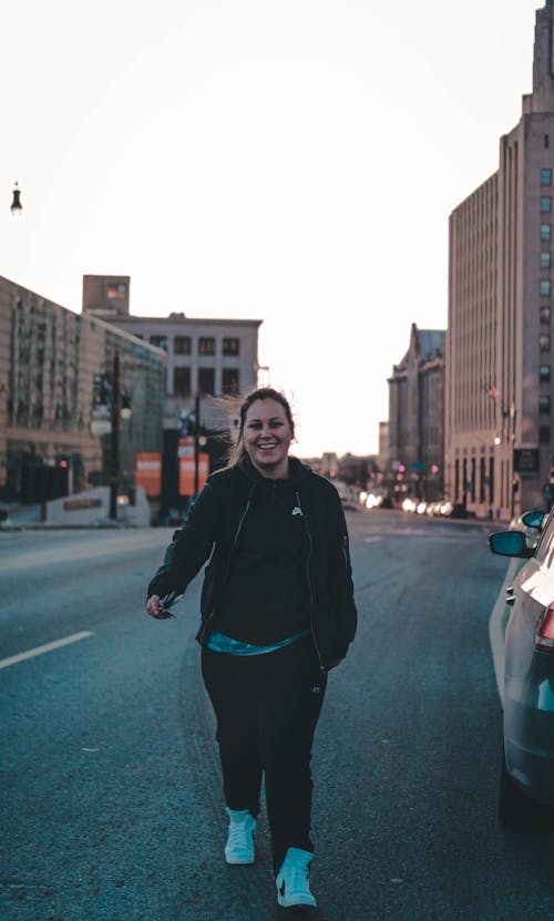 Woman in Black Jacket Walking on Road