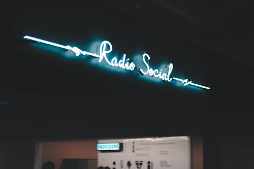 Creative design of title RADIO SOCIAL on signboard illuminating building and city street in dusk