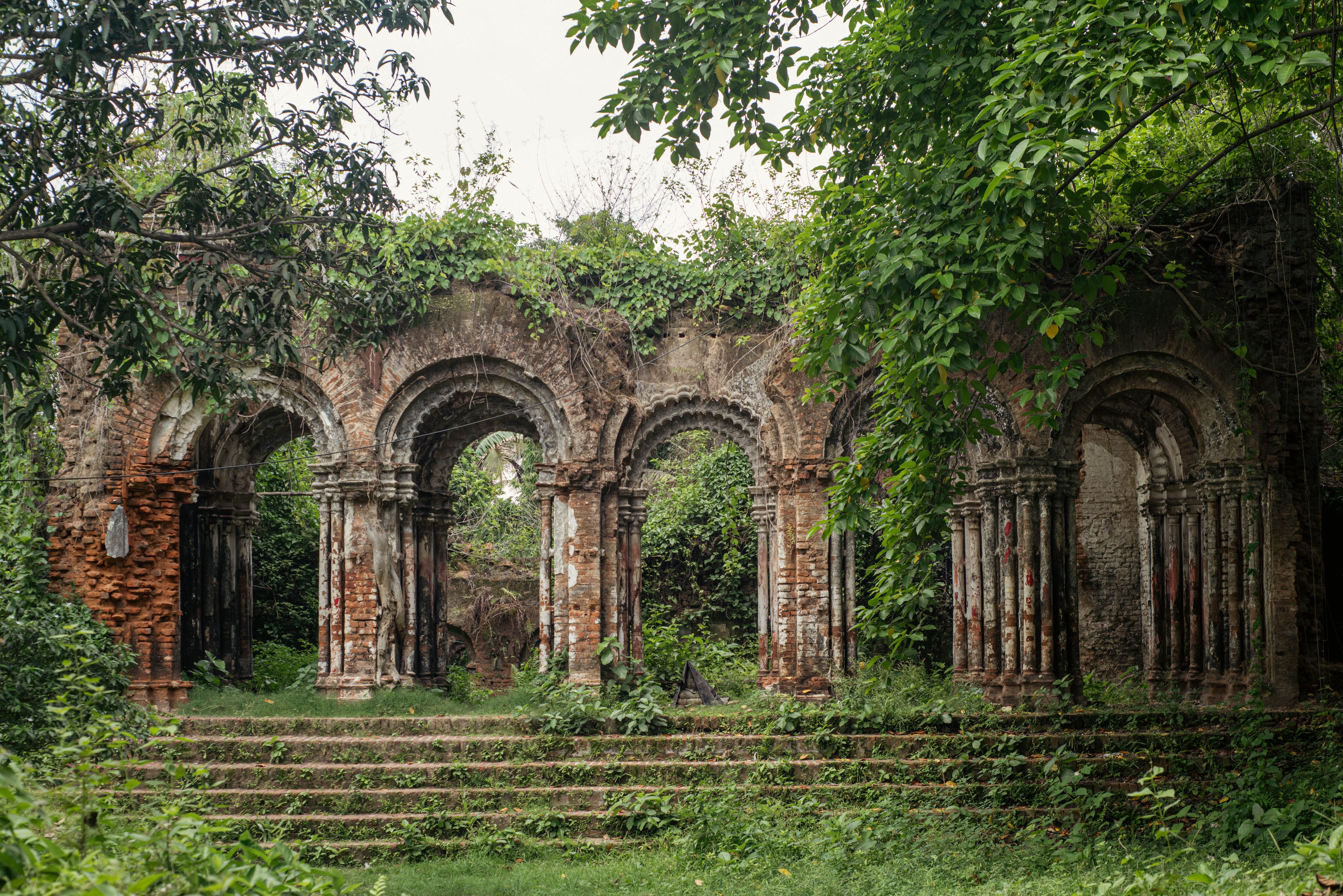 Historic brick ruins covered in lush greenery, showcasing architectural beauty and nature reclaiming structures.