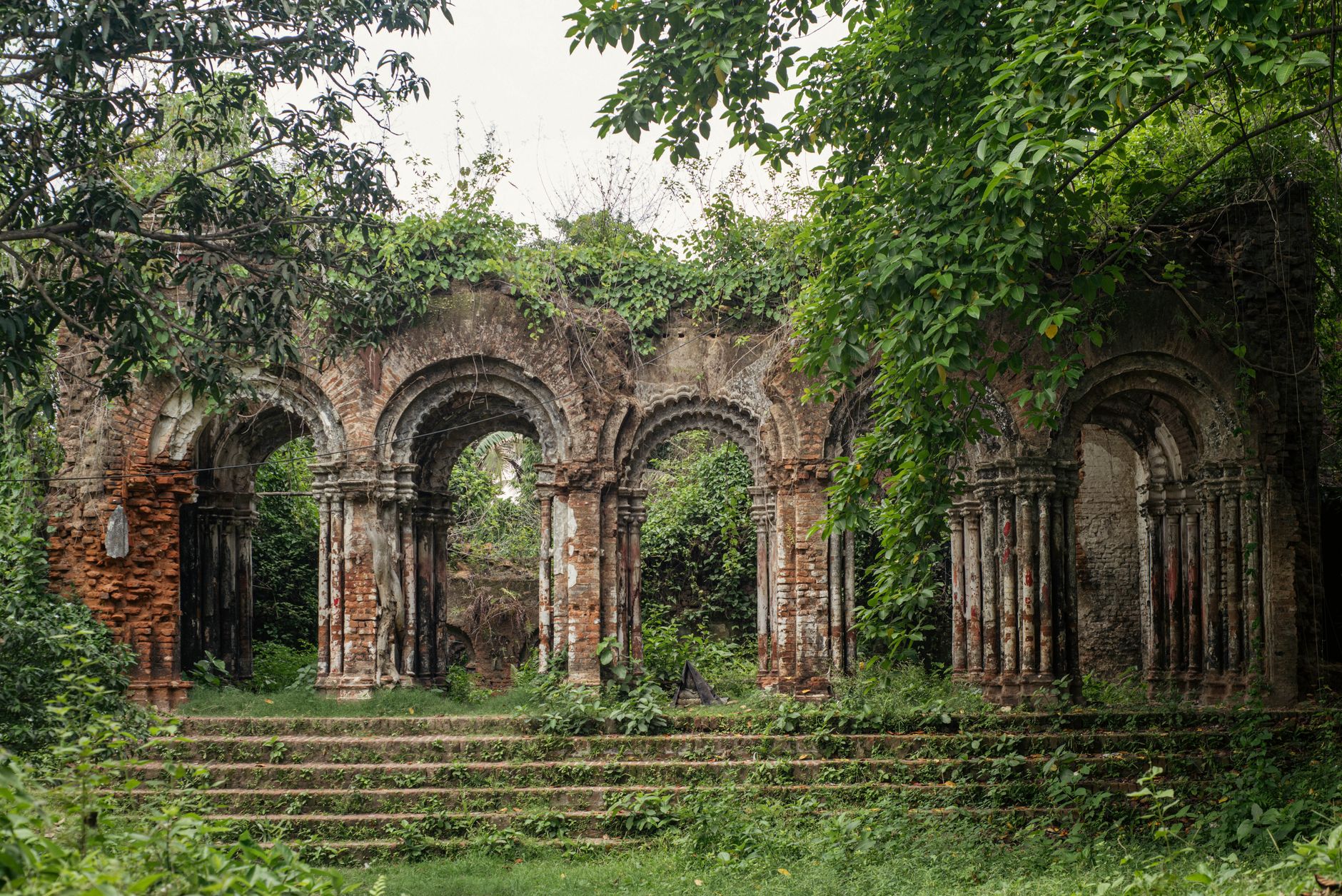 Historic brick ruins covered in lush greenery, showcasing architectural beauty and nature reclaiming structures.