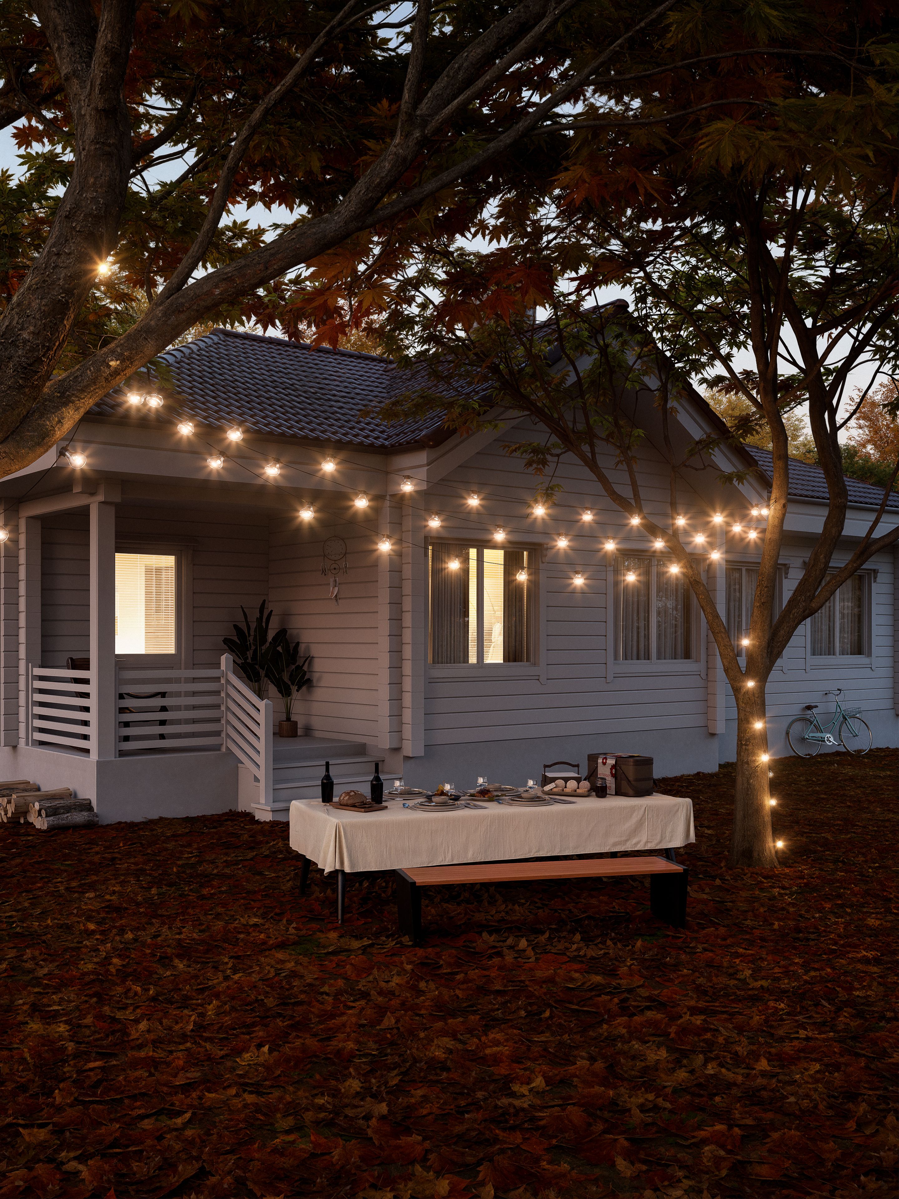 Charming evening outdoor dining setup under string lights and autumn leaves.