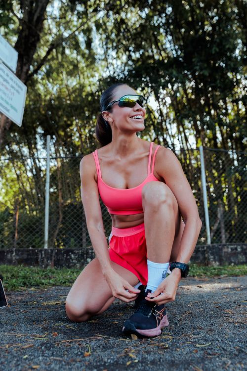 Free Smiling woman in sportswear tying her shoes on a sunny day in Pereira, Colombia. Stock Photo