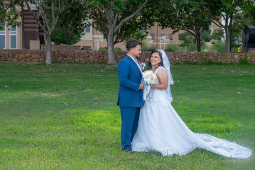 A bride and groom pose happily outdoors in wedding attire, showcasing love and joy.