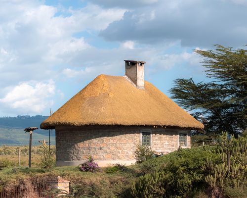 Free A picturesque stone hut with a thatched roof in Naivasha, Kenya surrounded by nature. Stock Photo