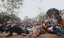 地面水平上，多民族人群聚集在绿色植物附近，看着相机