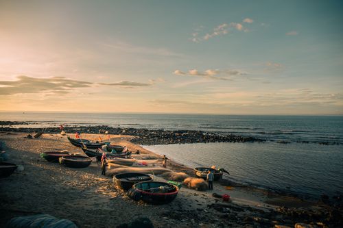 Free Scenic view of fishing boats and fishermen at Cửa Tùng Beach during sunset in Quảng Trị, Vietnam. Stock Photo