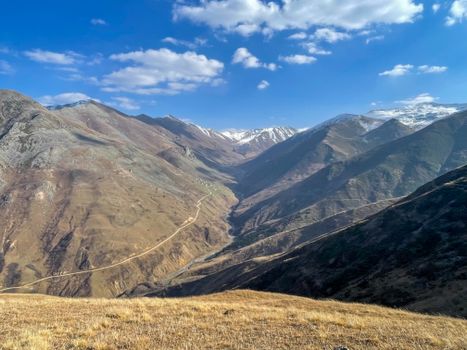 Breathtaking view of expansive mountain valleys with a winding road and clear blue sky, perfect for nature and travel enthusiasts.