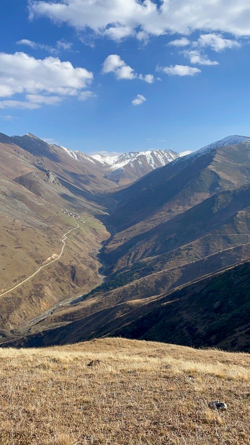 Free Explore scenic mountain valley with clear blue skies and rugged terrain. Stock Photo