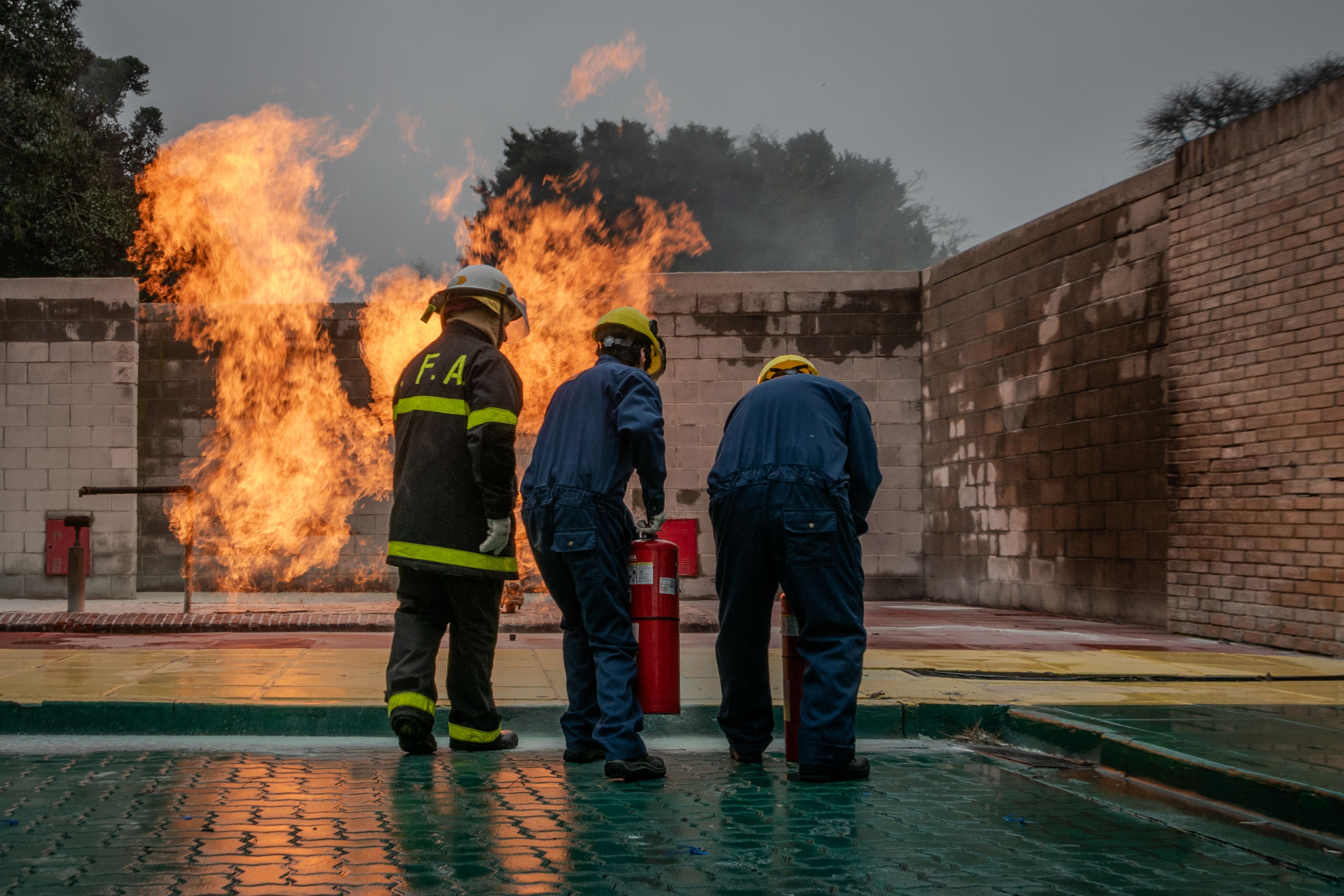 Group of firefighters in action using extinguisher during a training session with controlled fire.