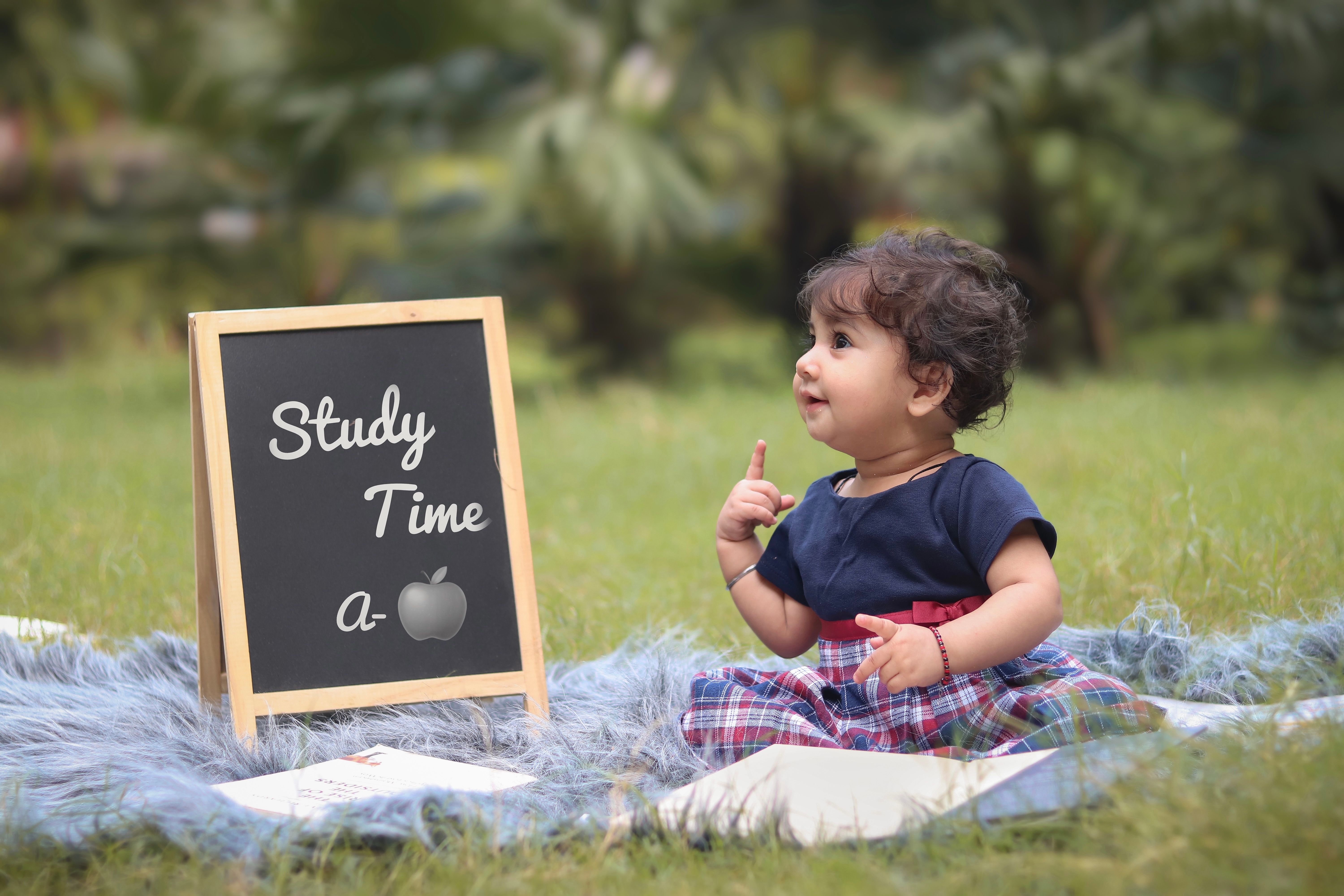 Cute baby studying with a chalkboard outdoors on a sunny day, enhancing early learning in a natural setting.