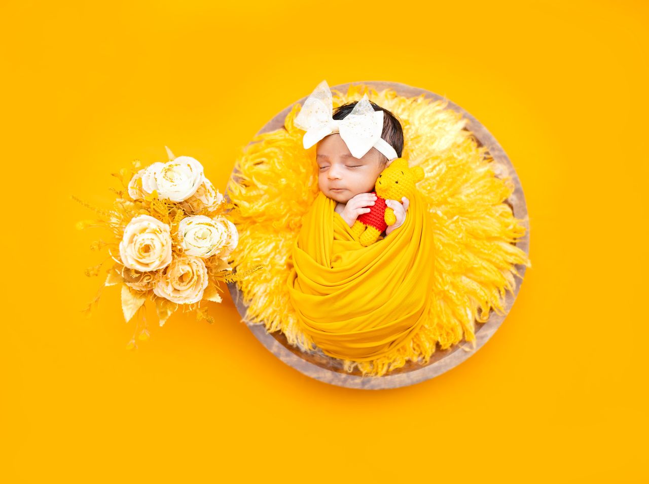 a sleeping newborn baby wrapped in yellow fabric surrounded by yellow