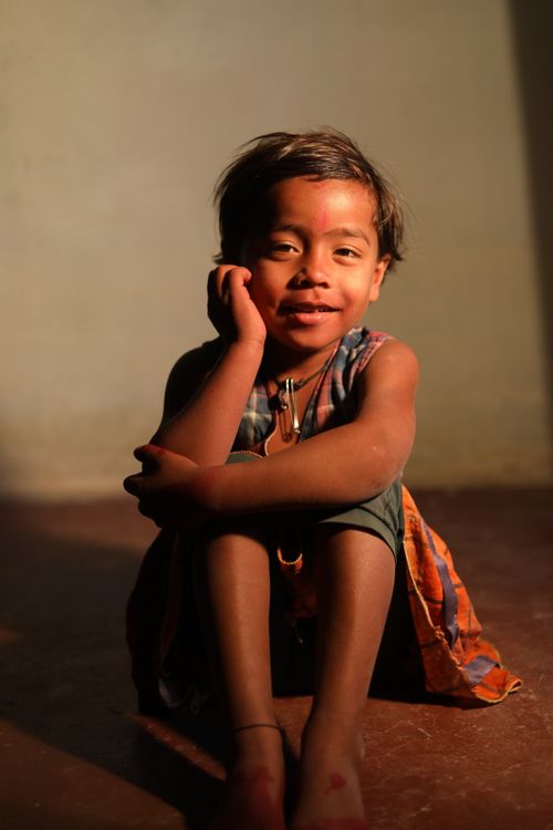 Free A joyful child sitting indoors, bathed in warm sunlight, with a peaceful expression. Stock Photo