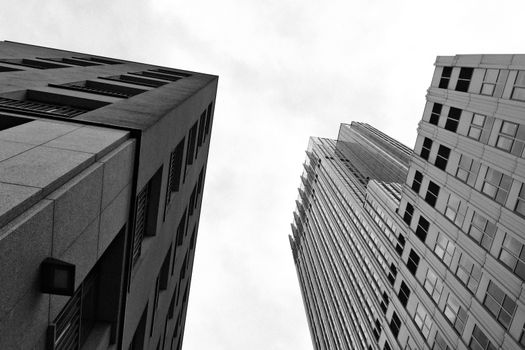 Striking black and white perspective of urban skyscrapers against a cloudy sky.