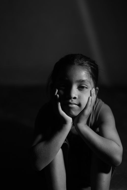 Free A black and white portrait of a thoughtful child sitting in quiet reflection. Stock Photo