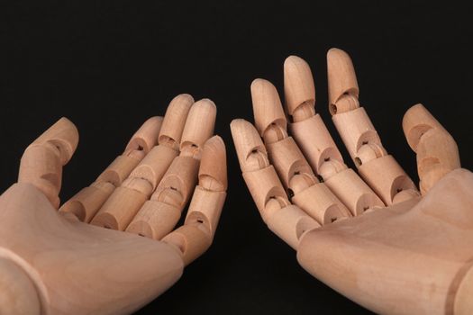 Close-up image of wooden articulated hands positioned against a dark background.