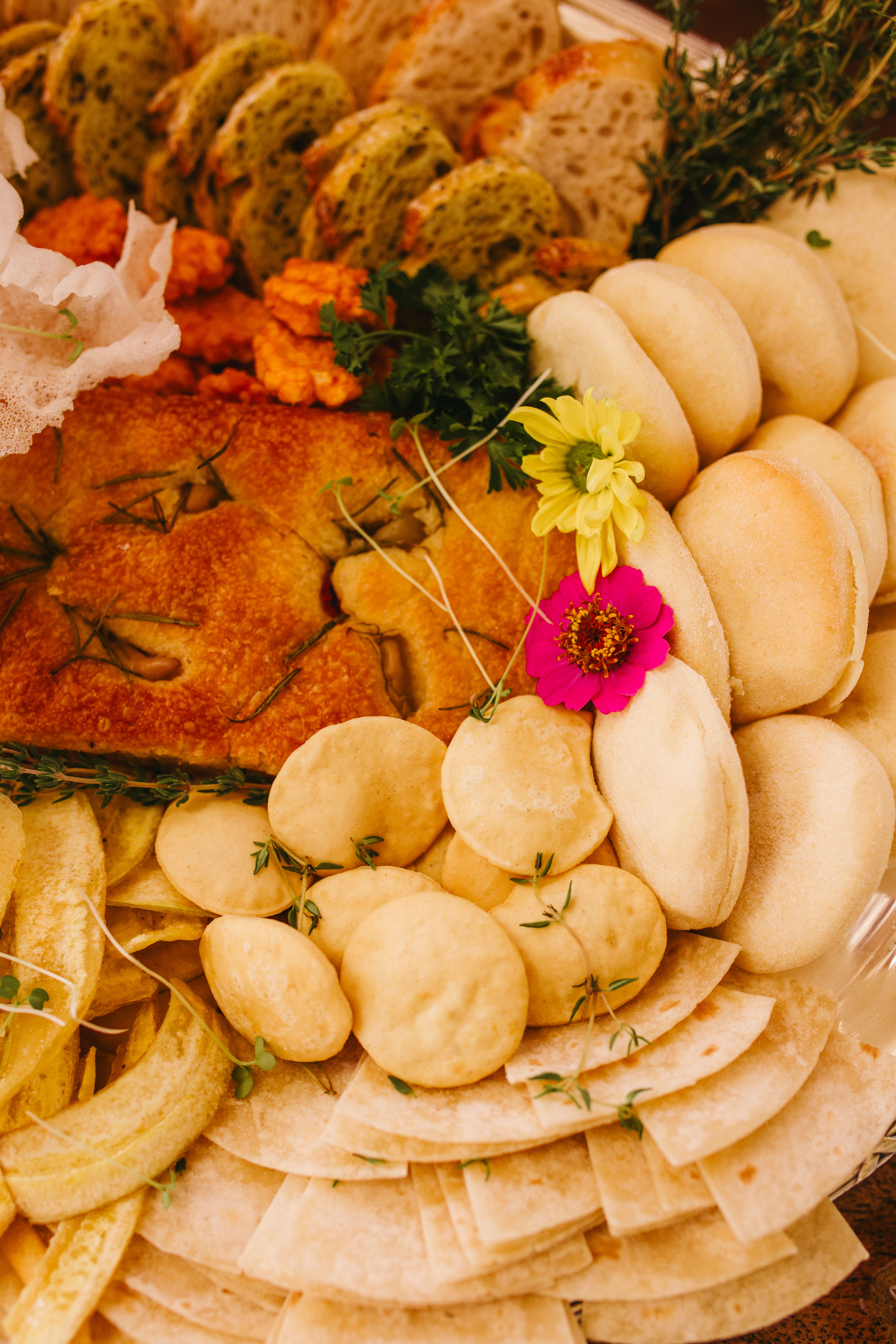 A rustic display of assorted artisan breads with fresh herbs and edible flowers.