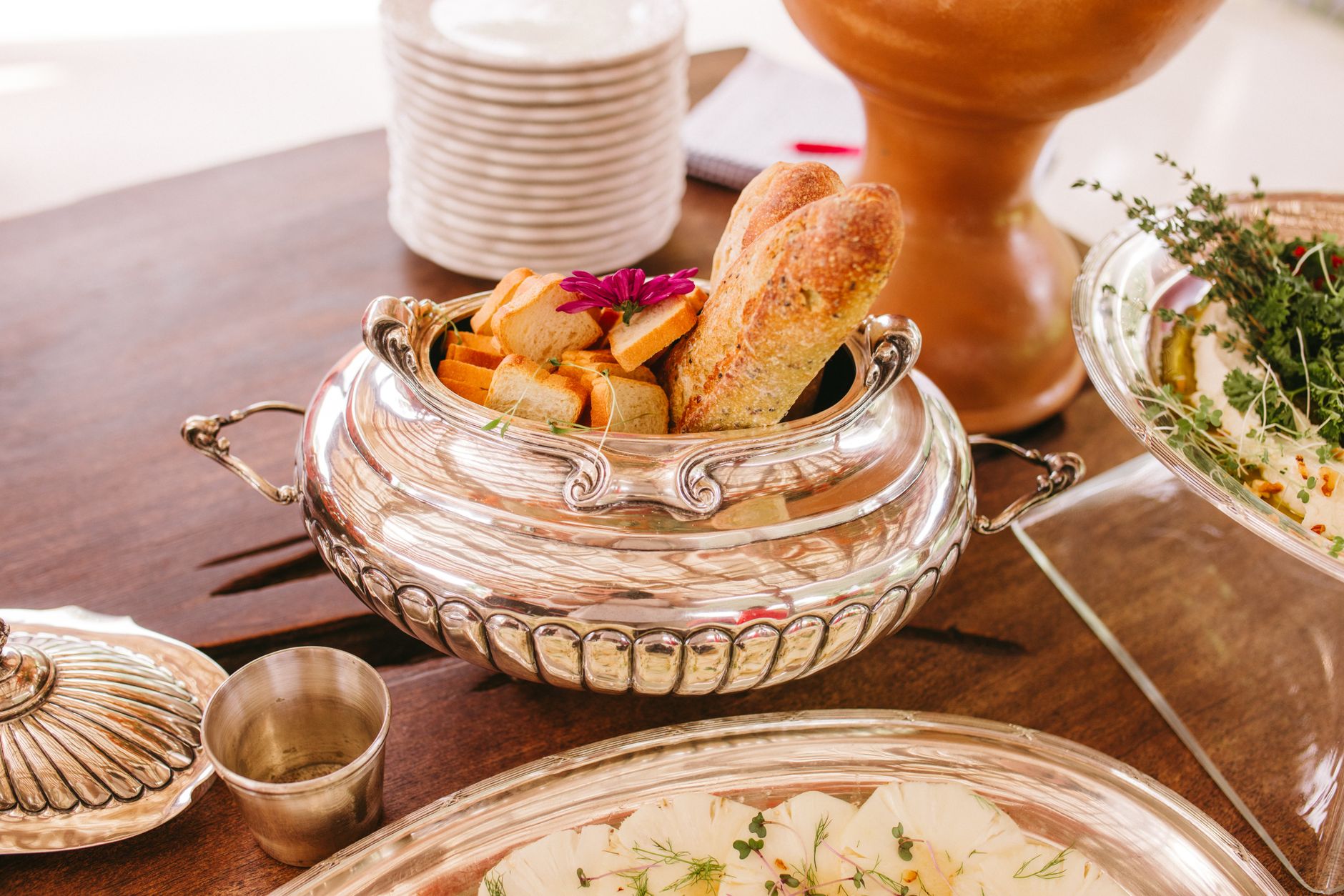 A sophisticated dining setup featuring fresh bread in a silver dish, perfect for weddings or gatherings.