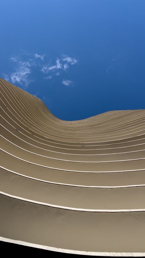Free Modern building facade with curved lines against a clear blue sky in MG, Brazil. Stock Photo