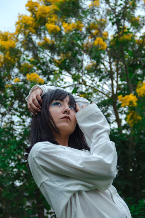 Free Stylish woman posing in front of vibrant yellow blossoms in São Paulo, Brazil. Stock Photo