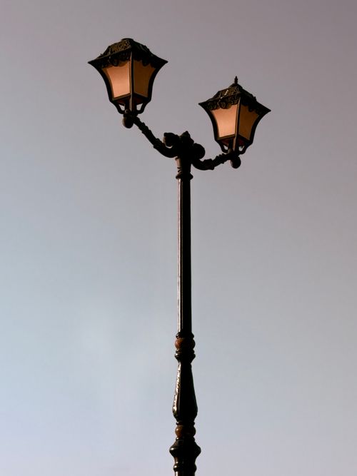 Free A vintage dual street lamp stands tall against a clear, pastel sky, highlighting classic design elements. Stock Photo