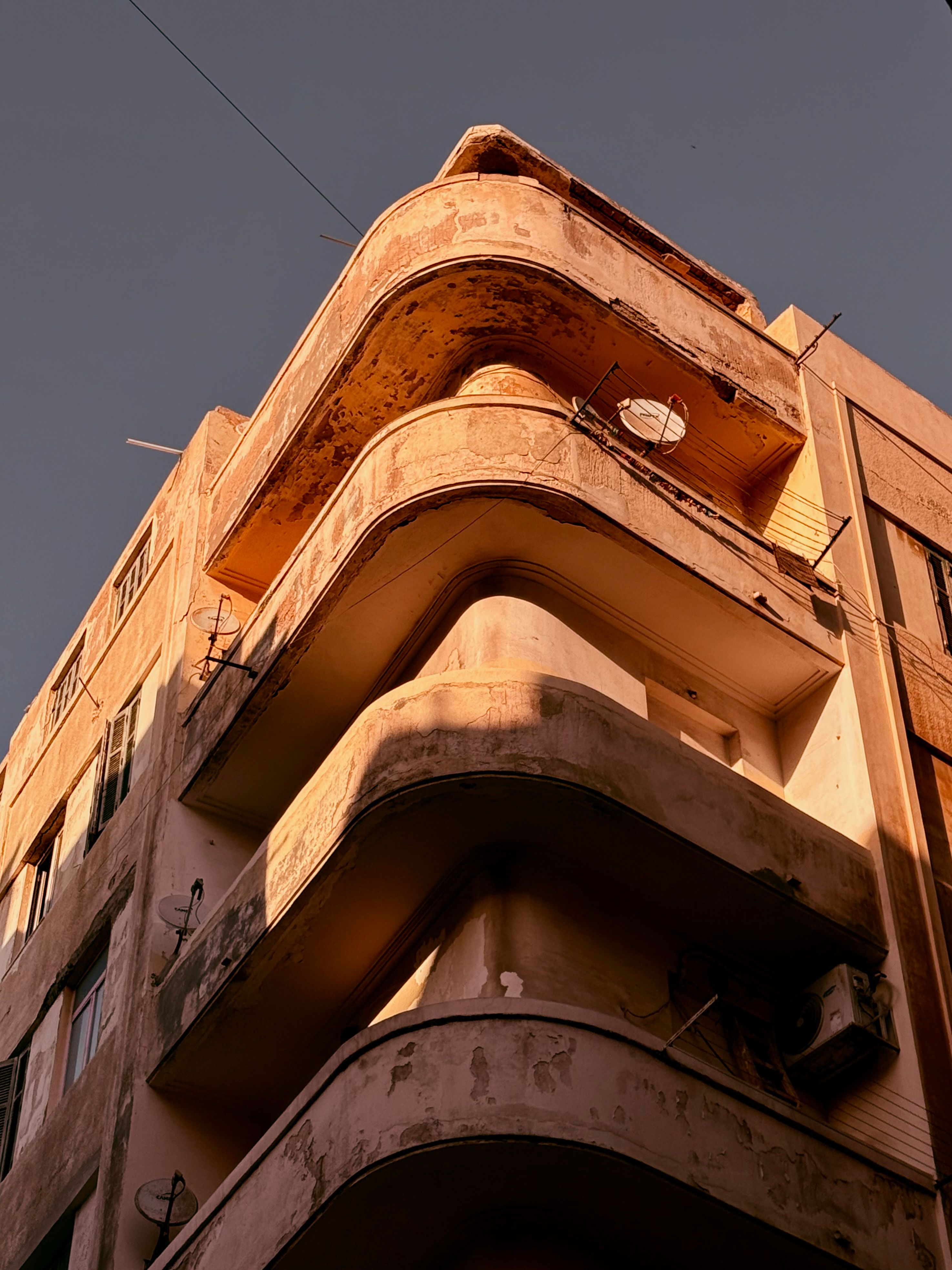 A vintage architectural building with curved balconies bathed in sunset light.