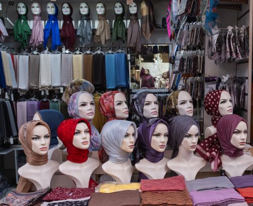 Free Vibrant array of hijabs on mannequins in a bustling Turkish fabric shop. Stock Photo