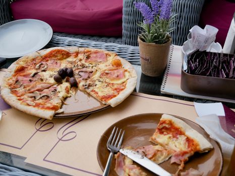 A tasty ham and mushroom pizza meal set on an outdoor table, perfect for a casual dining experience.