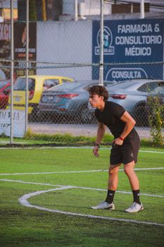 Teen soccer player in action on a city sports field during daytime.
