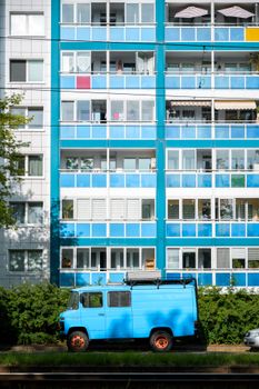 A vibrant blue apartment building with a blue van parked in front, showcasing urban Berlin architecture.