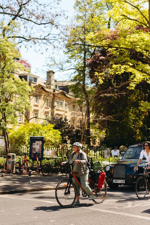 Free A sunny day in Oxford, UK with cyclists and classic cars passing by historic architecture. Stock Photo