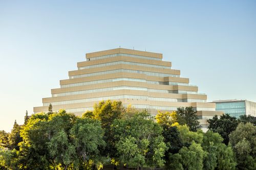 Free A unique tiered structure in a serene setting with lush green trees under clear sky. Stock Photo