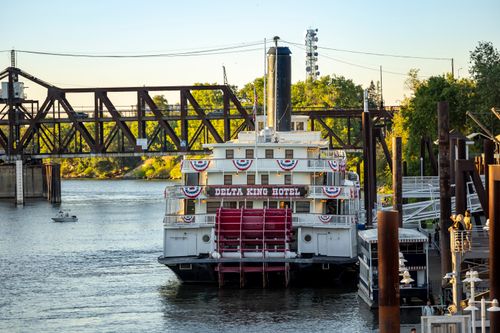 Free Delta King Hotel paddlewheel riverboat docked on the Sacramento River, with a bridge in the background. Stock Photo