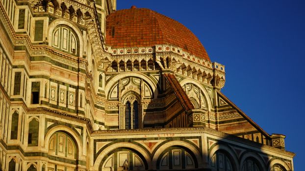 Close-up of the Florence Cathedral's dome and ornate facade during sunset.
